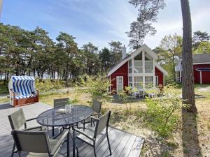 a patio with a table and chairs and a red barn at Ferienhaus Sandkörnchen - Strandpark - ca. 80m Strand in Baabe