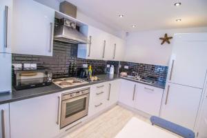 a kitchen with white cabinets and a stove top oven at Beachside Cottage - Camber Sands - Close to beach in Camber