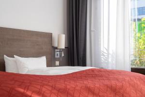 a bedroom with a bed with a red blanket and a window at Art & Business Hotel in Nürnberg