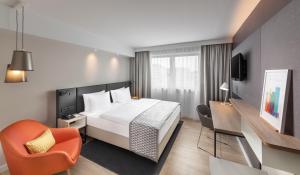 une chambre d'hôtel avec un lit et une chaise dans l'établissement Holiday Inn Munich City Centre, an IHG Hotel, à Munich