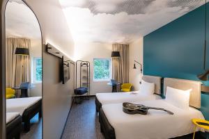 a hotel room with two beds and a mirror at Hotel ibis Lisboa Alfragide in Lisbon