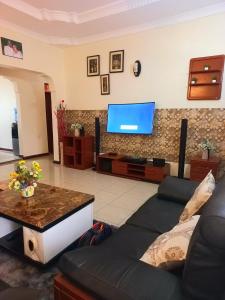 een woonkamer met een bank en een flatscreen-tv bij Ariel comfort home in Arusha