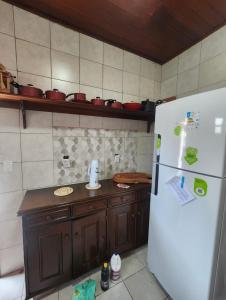 a kitchen with a white refrigerator and wooden cabinets at Casa Praia do Atalaia em Salinas Pará in Salinópolis