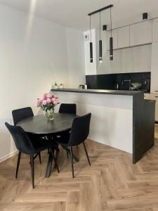 a dining room with a table and chairs and a kitchen at Przytulny apartament Klonowa 24-hour check-in Zameldowanie całodobowe in Kielce