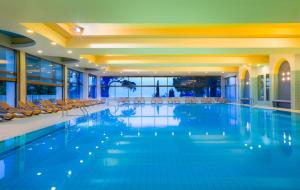 a large swimming pool with chairs in a building at Remisens CASA ROSA - Hotel Metropol Annexe in Portorož