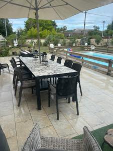 a table with chairs and an umbrella next to a pool at BARREAU in Libourne