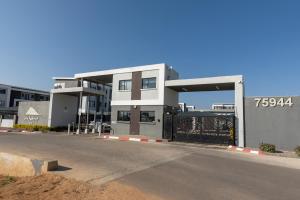 a building with a parking lot next to a street at One More Night Apartment E202 in Gaborone