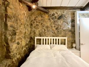 1 dormitorio con 1 cama en una pared de piedra en ［二館］九份沐石原宿MU SHI B&B兩人即包棟民宿 en Jiufen