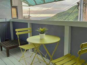 una mesa pequeña y sillas en un balcón con una planta en ［二館］九份沐石原宿MU SHI B&B兩人即包棟民宿, en Jiufen