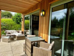 a patio with wicker chairs and a glass table at Peak District Romantic Retreat Outdoor Japanese Whirlpool bath in Stanton in Peak