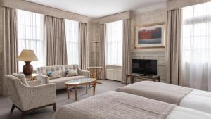 a hotel room with two beds a couch and a television at Wentworth Hotel in Aldeburgh