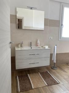 ein Badezimmer mit einem weißen Waschbecken und einem Spiegel in der Unterkunft Paola Confort House in Avola