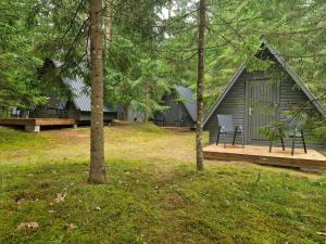 a cabin in the woods with a deck and a bench at Liivakõrtsi kämping in Rõmeda