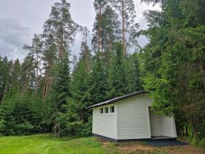 een klein wit gebouw midden in een bos bij Liivakõrtsi kämping in Rõmeda