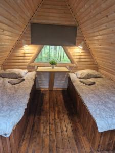 two beds in a wooden room with a window at Liivakõrtsi kämping in Rõmeda