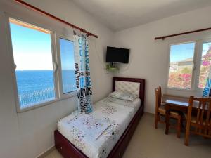 a bedroom with a bed and a table and windows at Prive Hill Saranda in Sarandë