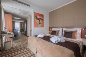 ein Hotelzimmer mit einem großen Bett mit Handtüchern darauf in der Unterkunft Business Hotel Astrum Laus in Levice