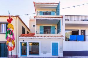 een wit gebouw met blauwe deuren en ramen bij Villa Belafonte in Câmara de Lobos