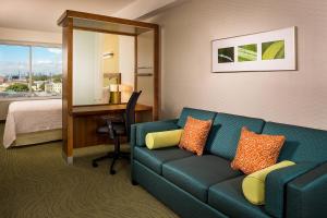 um quarto de hotel com um sofá e uma secretária em SpringHill Suites by Marriott New York LaGuardia Airport em Queens