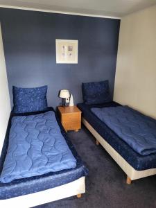 two beds in a room with blue sheets and a night stand at NV 206 - Beach Resort Nieuwvliet Bad in Nieuwvliet