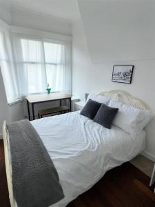 a bedroom with a white bed with pillows and a window at Modern Town House - Coventry in Coventry