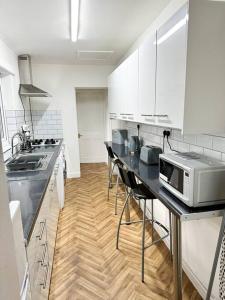 a kitchen with white cabinets and a counter with a microwave at Modern Town House - Coventry in Coventry