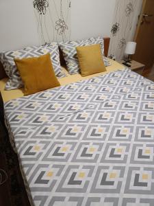 a bed with yellow and gray sheets and pillows at Apartman U2 in Veliko Gradište
