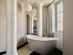a white bath tub in a bathroom with columns at The Crown Krakow Center - Handwritten Collection ACCOR in Kraków +97 photos