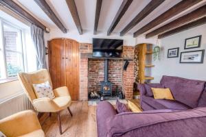 a living room with a purple couch and a fireplace at The Black House, Wangford in Beccles
