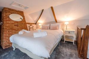 a bedroom with a large white bed with a brick wall at The Black House, Wangford in Beccles