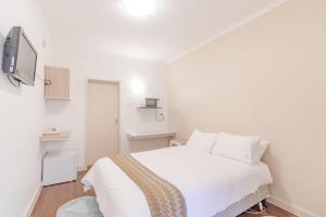 a white bedroom with a bed and a tv at Warburton Lodge in Warburton