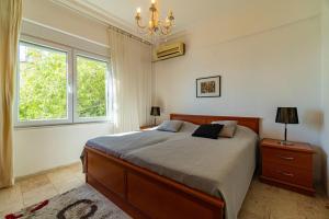 a bedroom with a bed and a chandelier and two windows at In the hearth of city, seaview. in Alanya
