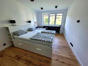 a white bedroom with a large bed and a window at Apartament Wrzos in Cisna