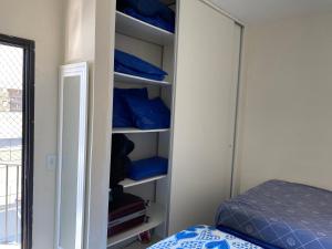 ein Schrank mit blauen Kissen und ein Bett in einem Zimmer in der Unterkunft Enseada guaruja in Guarujá