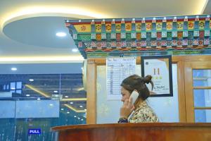 uma mulher a falar ao telefone num pódio em The BD Hotel em Thimphu