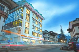 Un grand bâtiment avec des voitures garées devant lui dans l'établissement The BD Hotel, à Thimphou
