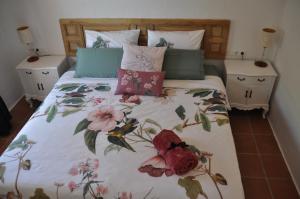 a bed with a floral comforter with two night stands at Boutique B&B El Refugio in Alcaucín