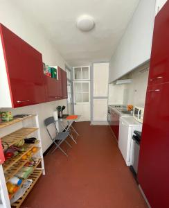 ミヨーにあるRésidence du bord du Tarnの赤いキャビネットとテーブル付きのキッチンが備わります。