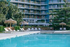 a swimming pool with chairs and a hotel in the background at Hotel Almirante in Alicante