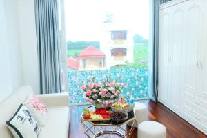 ハノイにあるNoi Bai Ville Airport Hotelのリビングルーム(白いソファ、花のテーブル付)