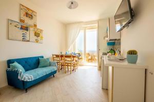 a living room with a blue couch and a kitchen at FinisTerrae Rooms and Suites in Gagliano del Capo
