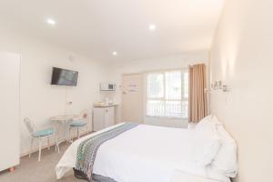 een witte slaapkamer met een bed en een tafel bij Warburton Lodge in Warburton