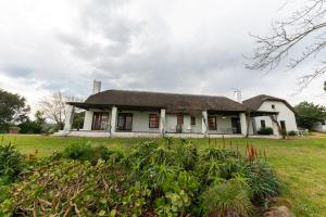 an old white house with a grassy yard at Saxenburg Wine Farm in Kuilsrivier