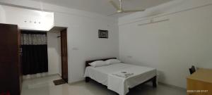 een witte slaapkamer met een bed en een plafond bij PAZHOOR RESIDENCY HOME STAY THREE BED ROOM Deluxe in Trivandrum