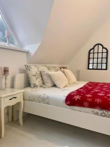 Farmhouse Dženi في فلاسيتش: غرفة نوم بيضاء مع سرير وبطانية حمراء