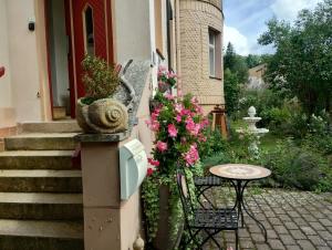 um pátio com uma mesa e flores ao lado de uma casa em Ferienwohnung in der Kunst und Kultur Villa Bad Steben em Bad Steben