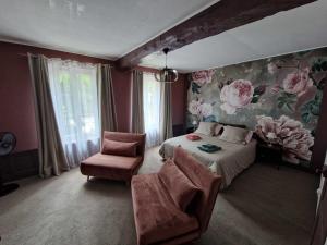 a bedroom with a bed and a chair and flowers on the wall at ESCALE AU CLOS SAINT MARTIN DE JUILLERS Gîtes et Chambres d'hôtes in Saint-Martin-de-Juillers +69 photos