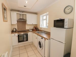 a kitchen with white cabinets and a clock on the wall at 106 Westgate in Guisborough