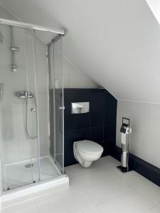 a bathroom with a glass shower and a toilet at Hotel Dana in Bytów