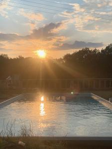 einen Pool mit Sonnenuntergang im Hintergrund in der Unterkunft Gîte du ru d ausson in Avrigny